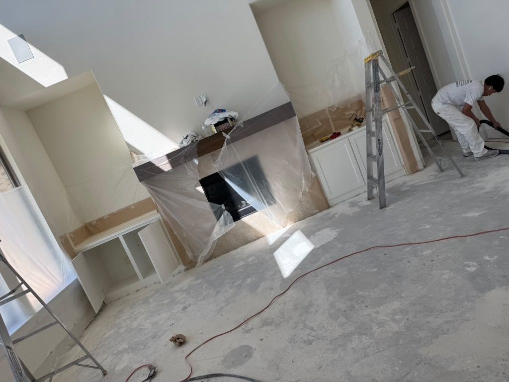 Renovation in progress in a room with ladders, tools, and workers near a large wall opening