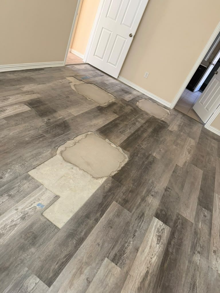 Damaged hardwood-style floor with missing planks in a hallway near white doors.