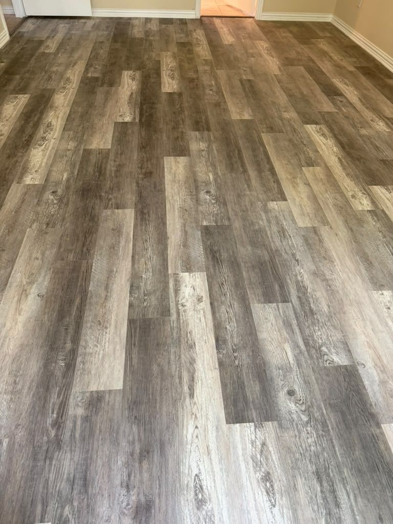 Empty room with gray-brown wood plank flooring and white baseboards