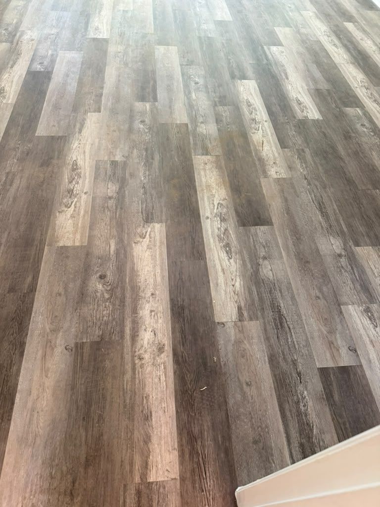 Empty room with gray-brown wood flooring and a white wall corner