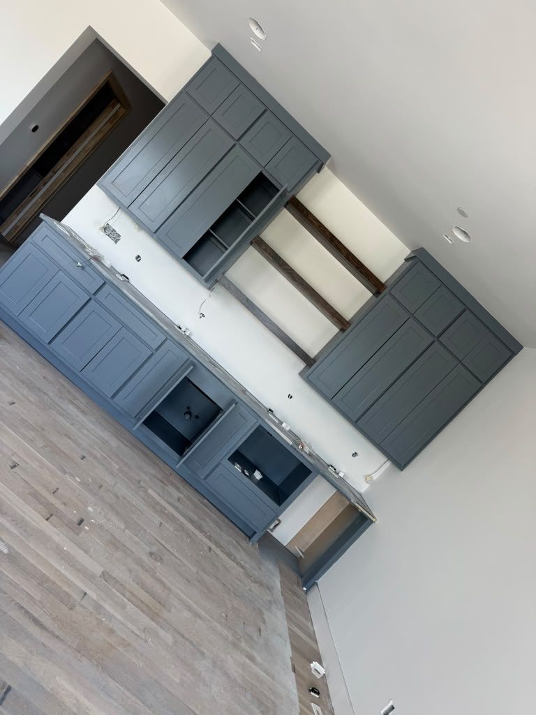 Empty modern kitchen with gray cabinets, white walls, and wood flooring, slightly tilted view