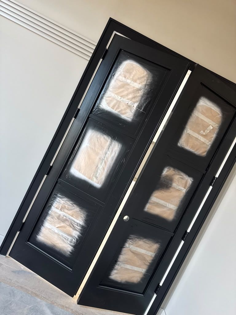 Black front door with six frosted glass panels and silver handle, slightly tilted view indoors