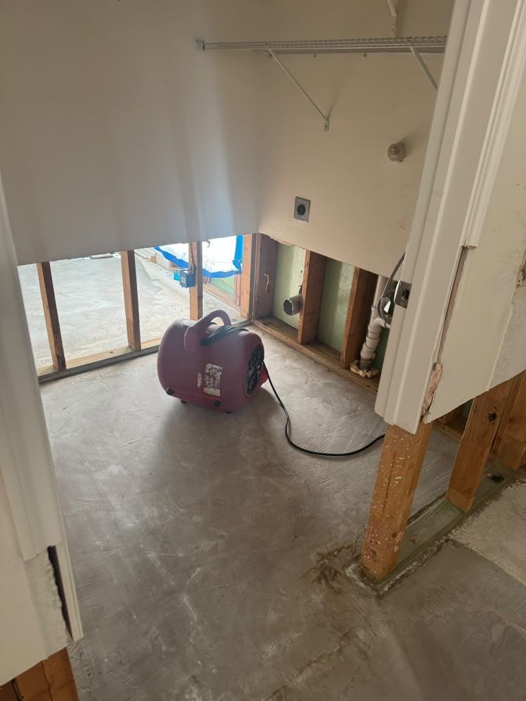 Construction site interior with purple dehumidifier, exposed beams, and concrete floor near large windows