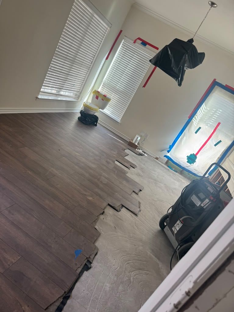 Empty room with dark wood flooring, a central torn carpet strip, and windows with blinds.