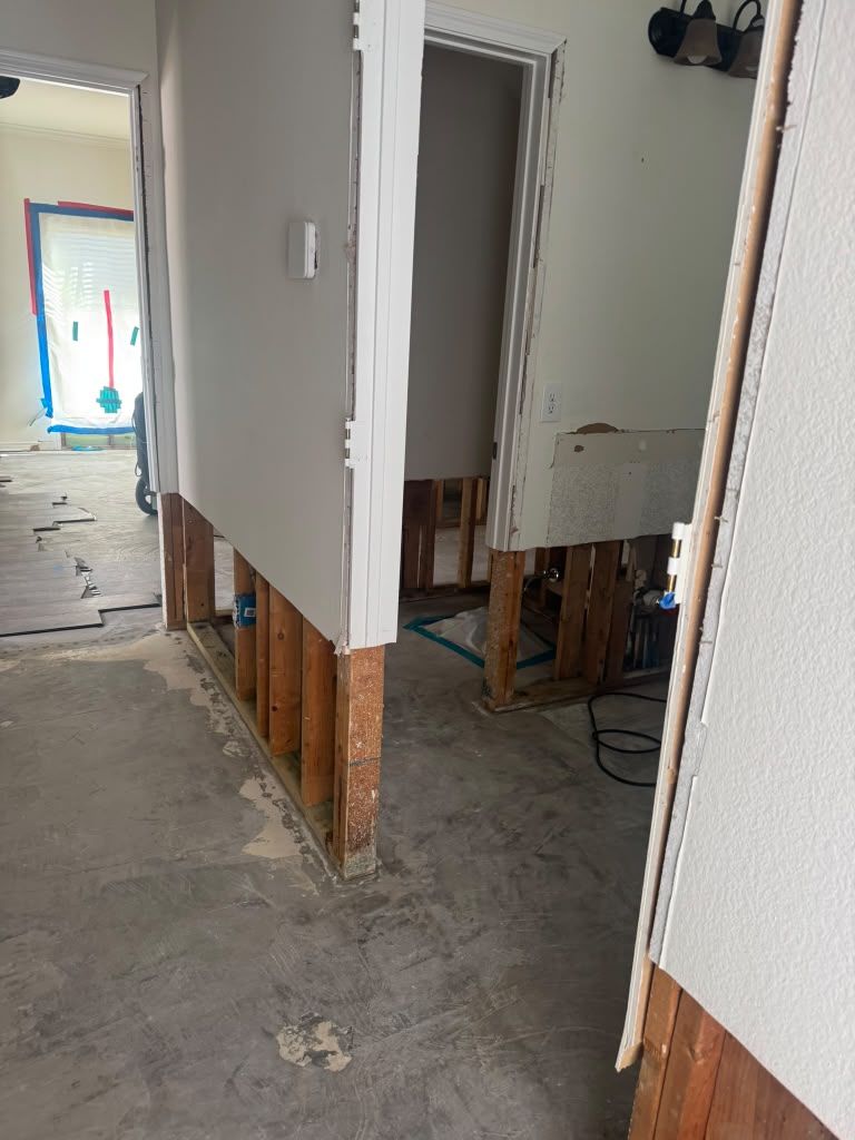 Interior hallway under renovation with exposed wall framing and unfinished drywall edges.