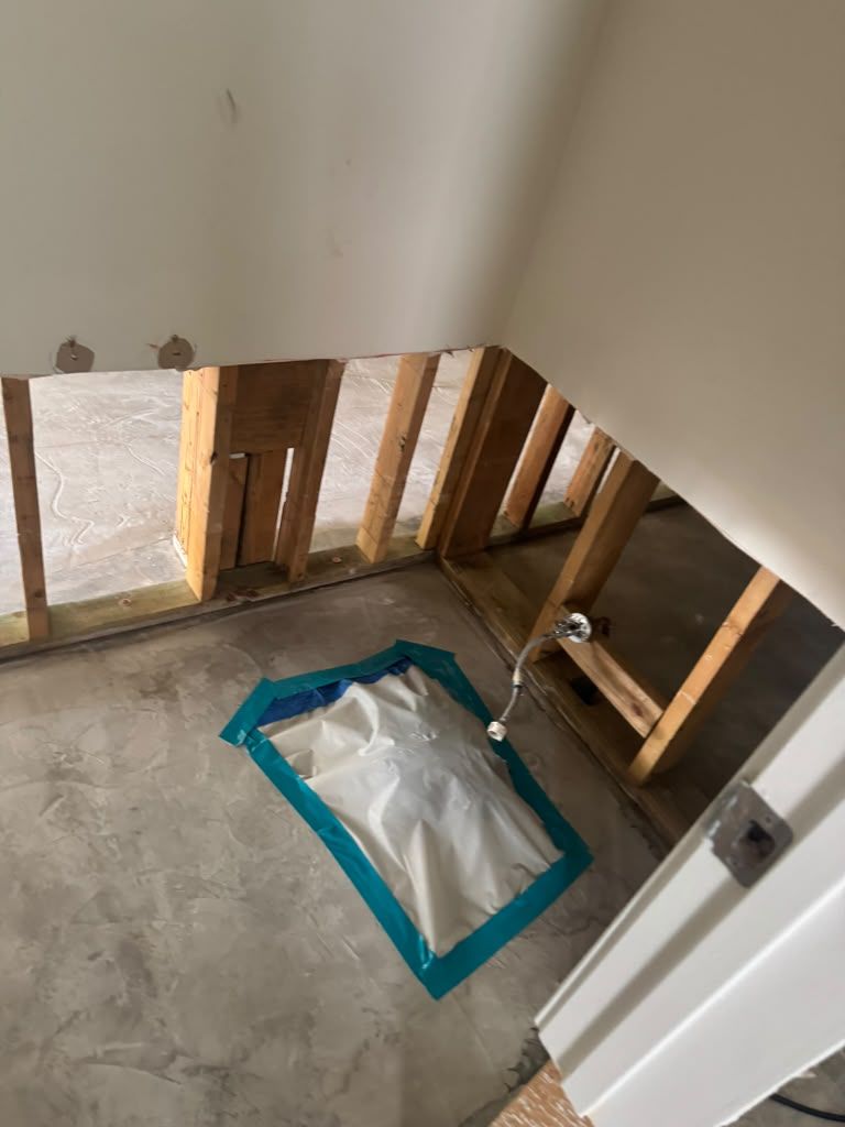 Partially renovated stair landing with exposed wall studs and a taped floor protection sheet