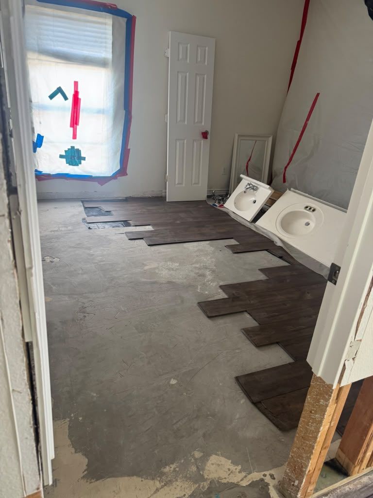 Unfinished room with gray floor, window, door, and wall panels leaning on the right.
