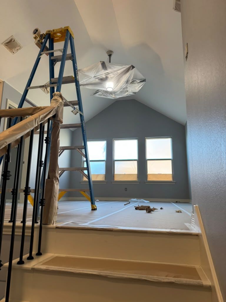 Open staircase under construction with blue ladder, hanging plastic, and windows in a bright room