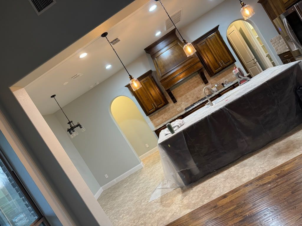Modern kitchen with island, pendant lights, arched doorways, and tiled floor