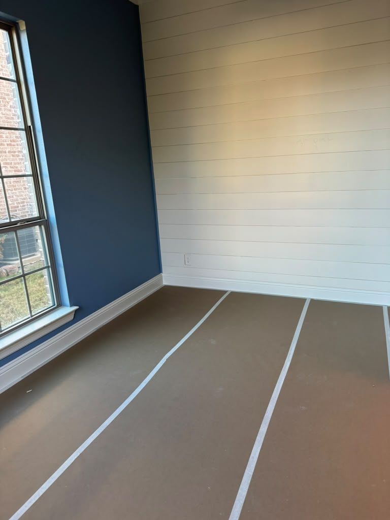 Small empty room with dark blue wall, white shiplap accent wall, window, and unfinished floor markings