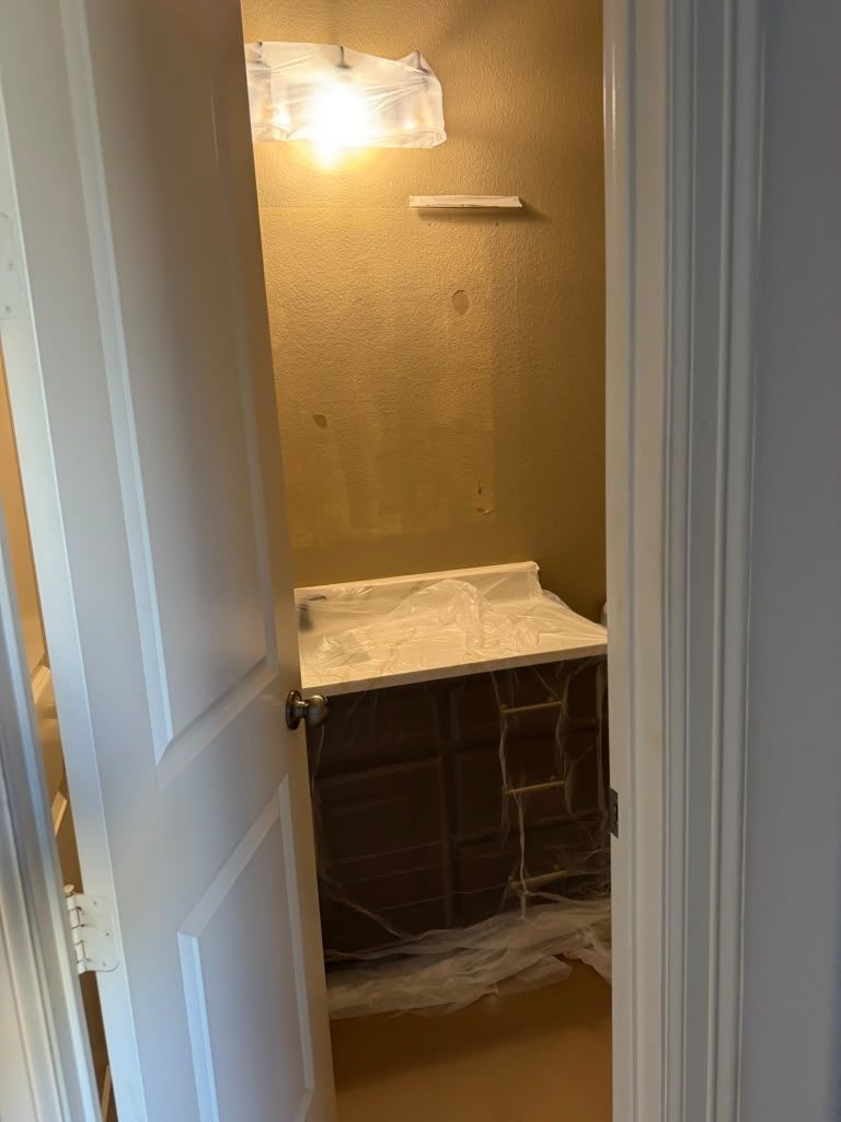 Bathroom vanity and mirror through a doorway, with a light above and a dark cabinet below.