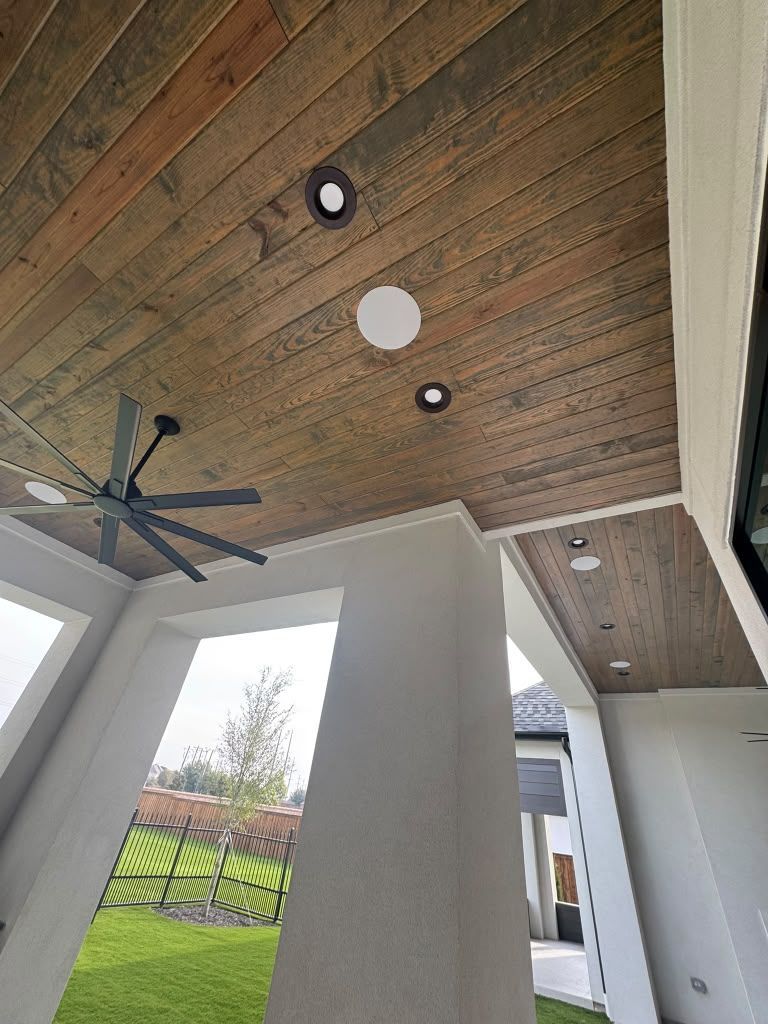 Covered patio with wood ceiling, black ceiling fan, and recessed lights overlooking a yard