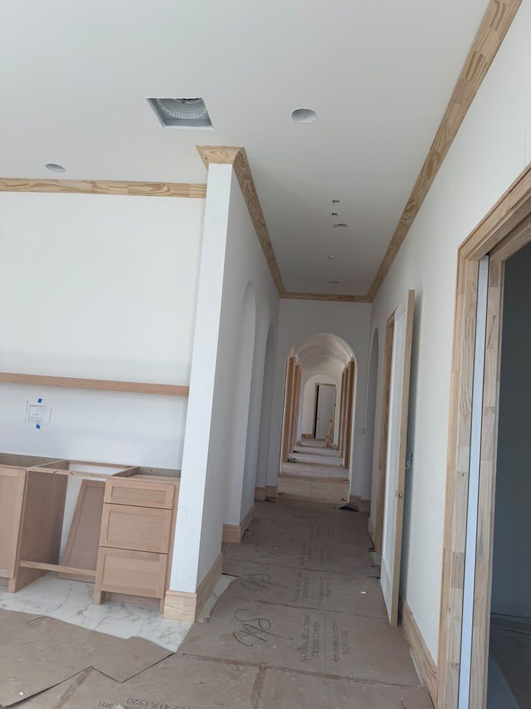 Unfinished hallway with white walls, tiled floor, arched doorways, and a kitchen counter on the left.