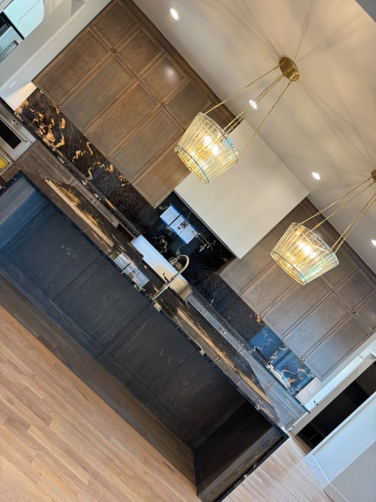 Modern hotel reception desk with dark wood cabinetry, marble counter, and hanging pendant lights