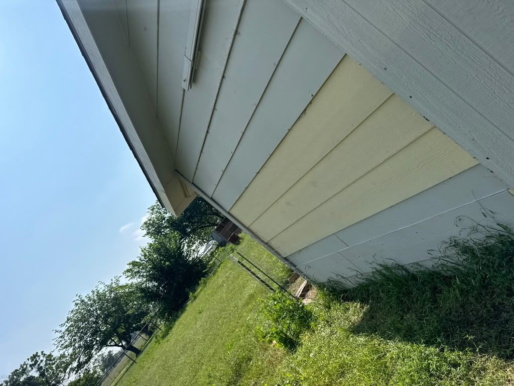 Side of a white house beside a grassy yard under a blue sky