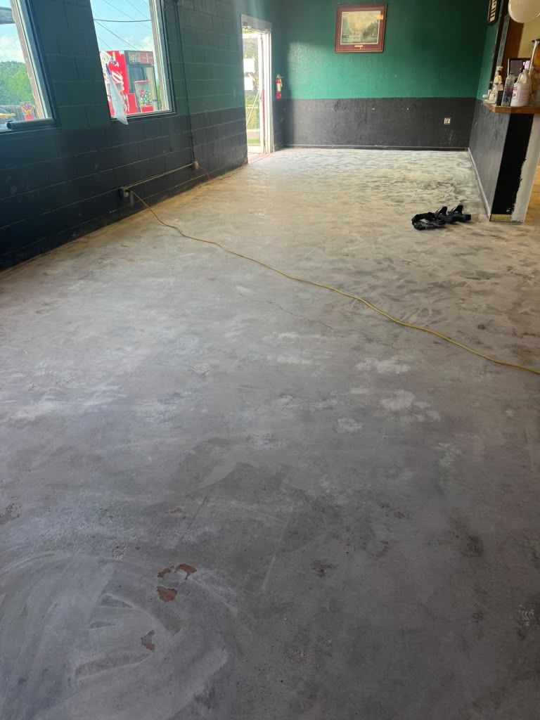 Empty room with concrete floor, green walls, and a pair of shoes near the far wall.
