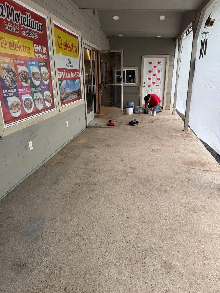 Covered outdoor school walkway with bulletin boards and a person crouching near a door