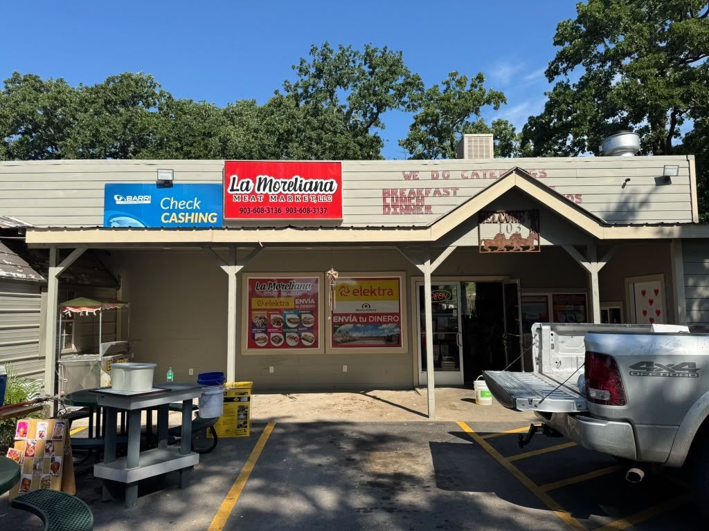 Strip mall storefronts with Thai restaurant and candy shop signs, outdoor seating, and parked cars