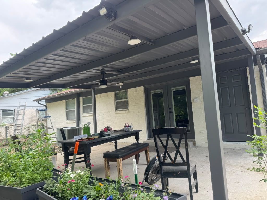 Patio with a metal roof, outdoor table and chairs, potted plants, and a beige house in the background