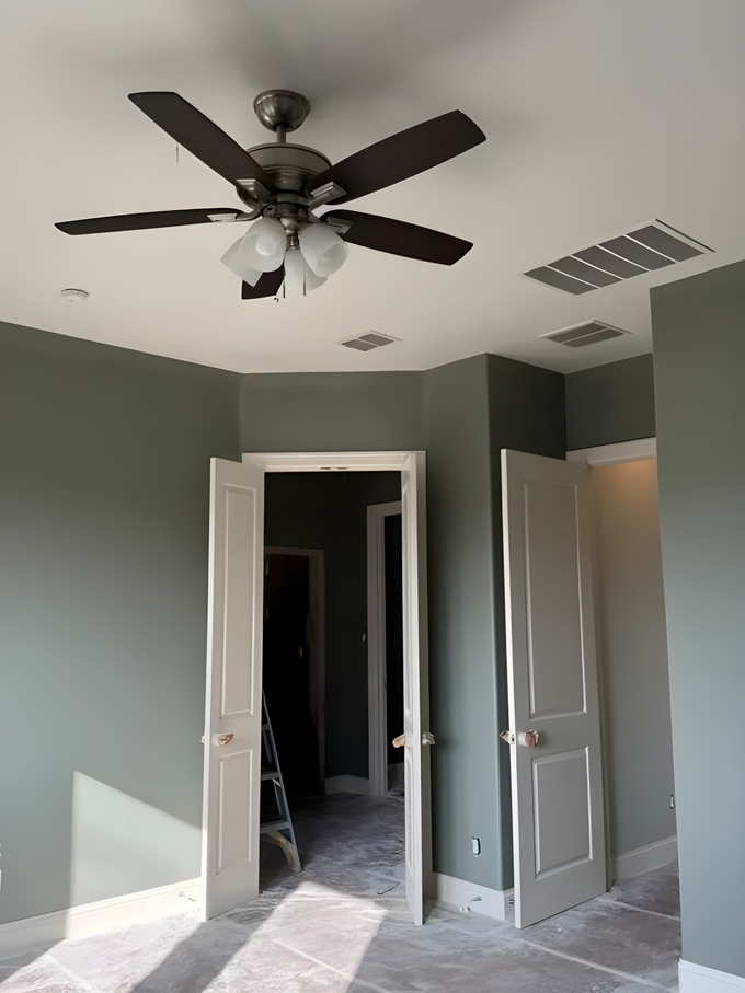 Empty room with green walls, ceiling fan, open doors, and a partially tiled floor under construction