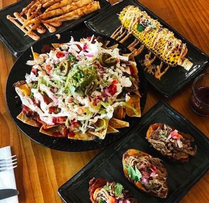 A table displays a spread of Mexican food: nachos, corn