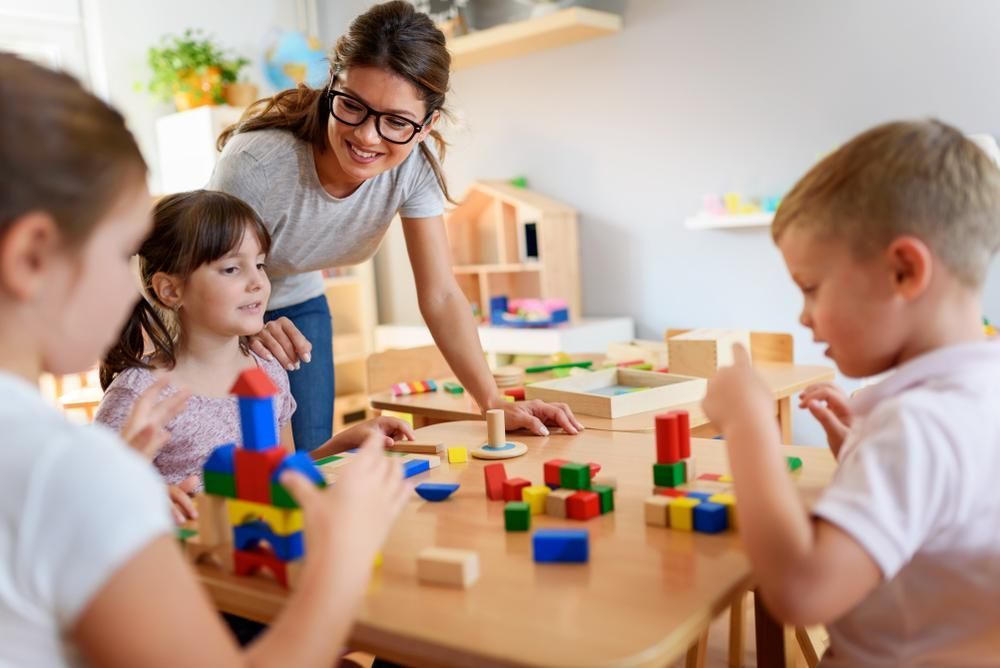 A Teacher Is Teaching a Group of Children how To Play with Wooden Blocks — Al Roberts Education Centre in Wynnum West, QLD