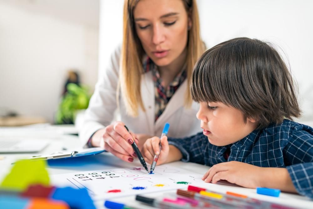 A Woman Is Teaching a Young Boy how To Draw with Markers — Al Roberts Education Centre in Wynnum West, QLD