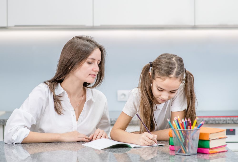 A woman is helping a young girl with her work — Al Roberts Education Centre in Wynnum West, QLD