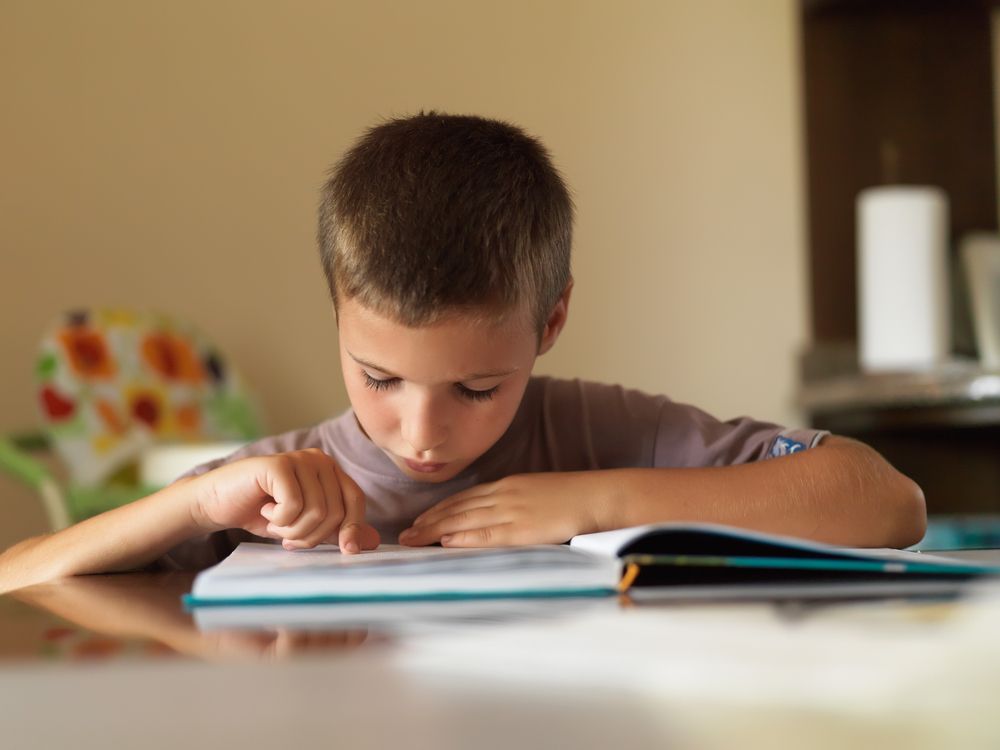 Boy Reading A Book On A Table — Al Roberts Education Centre in Wynnum West, QLD