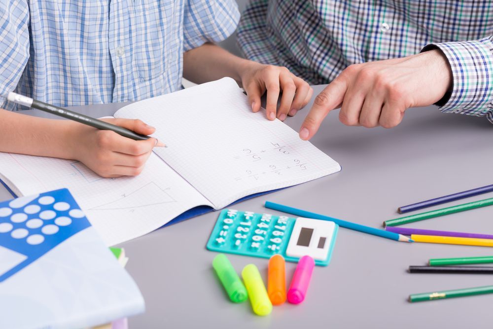 A Man And A Child Are Sitting at A Table Doing Their Homework — Al Roberts Education Centre in Wynnum West, QLD