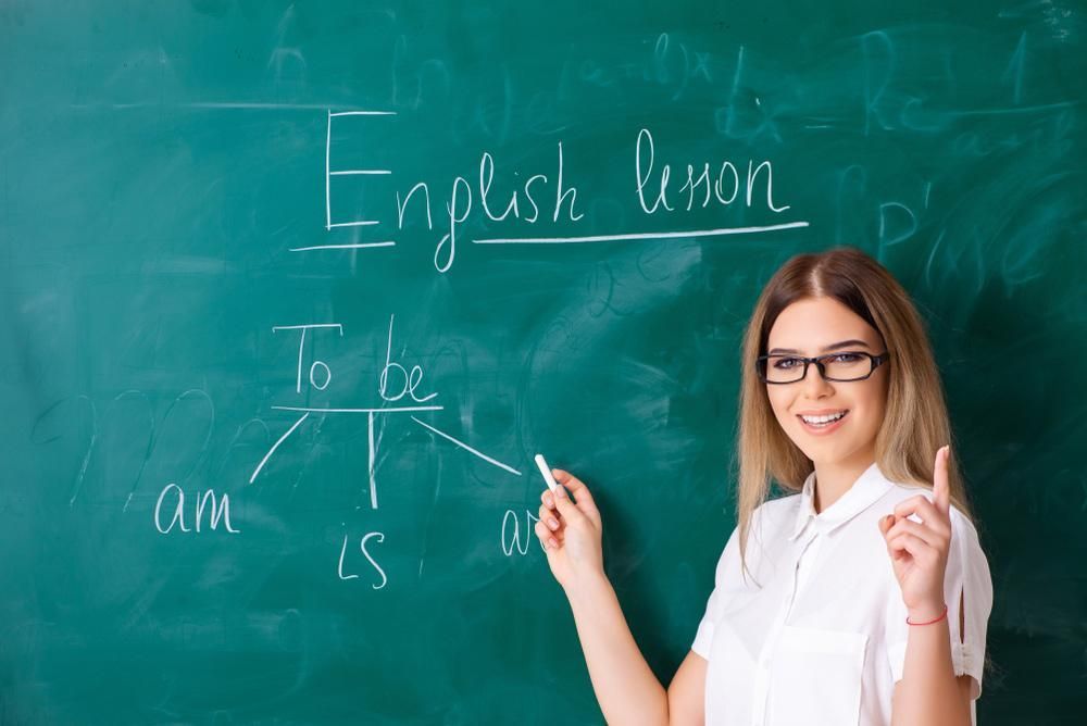 A Woman Is Standing in Front of A Blackboard Writing on It — Al Roberts Education Centre in Wynnum West, QLD