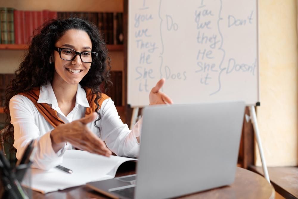 A Woman Is Sitting at A Table with A Laptop and A Whiteboard — Al Roberts Education Centre in Wynnum West, QLD