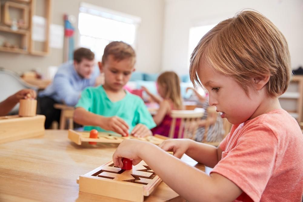 A Young Boy Is Playing with A Wooden Toy in A Classroom — Al Roberts Education Centre in Wynnum West, QLD