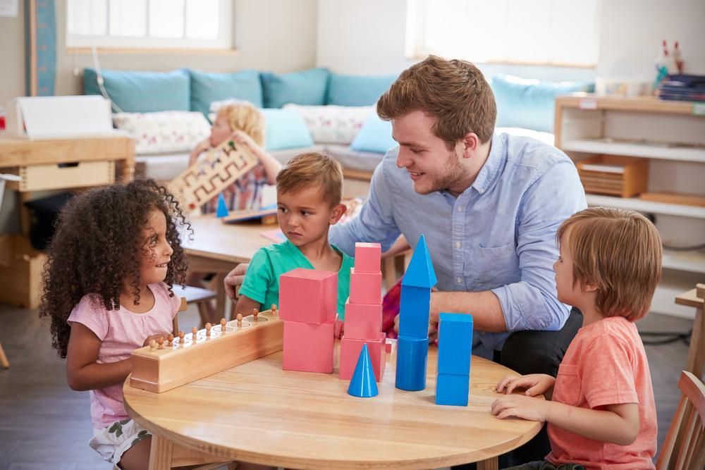 A Teacher Is Playing with Children at A Table in A Classroom — Al Roberts Education Centre in Wynnum West, QLD