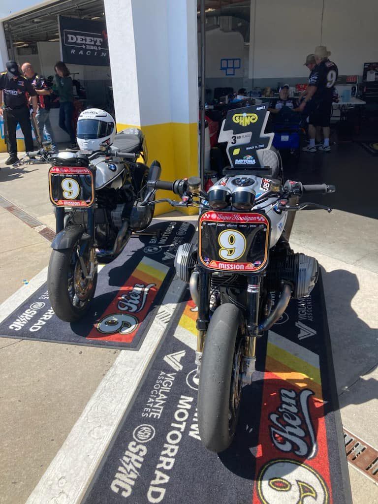 Two motorcycles are parked on a mat that says motorrad