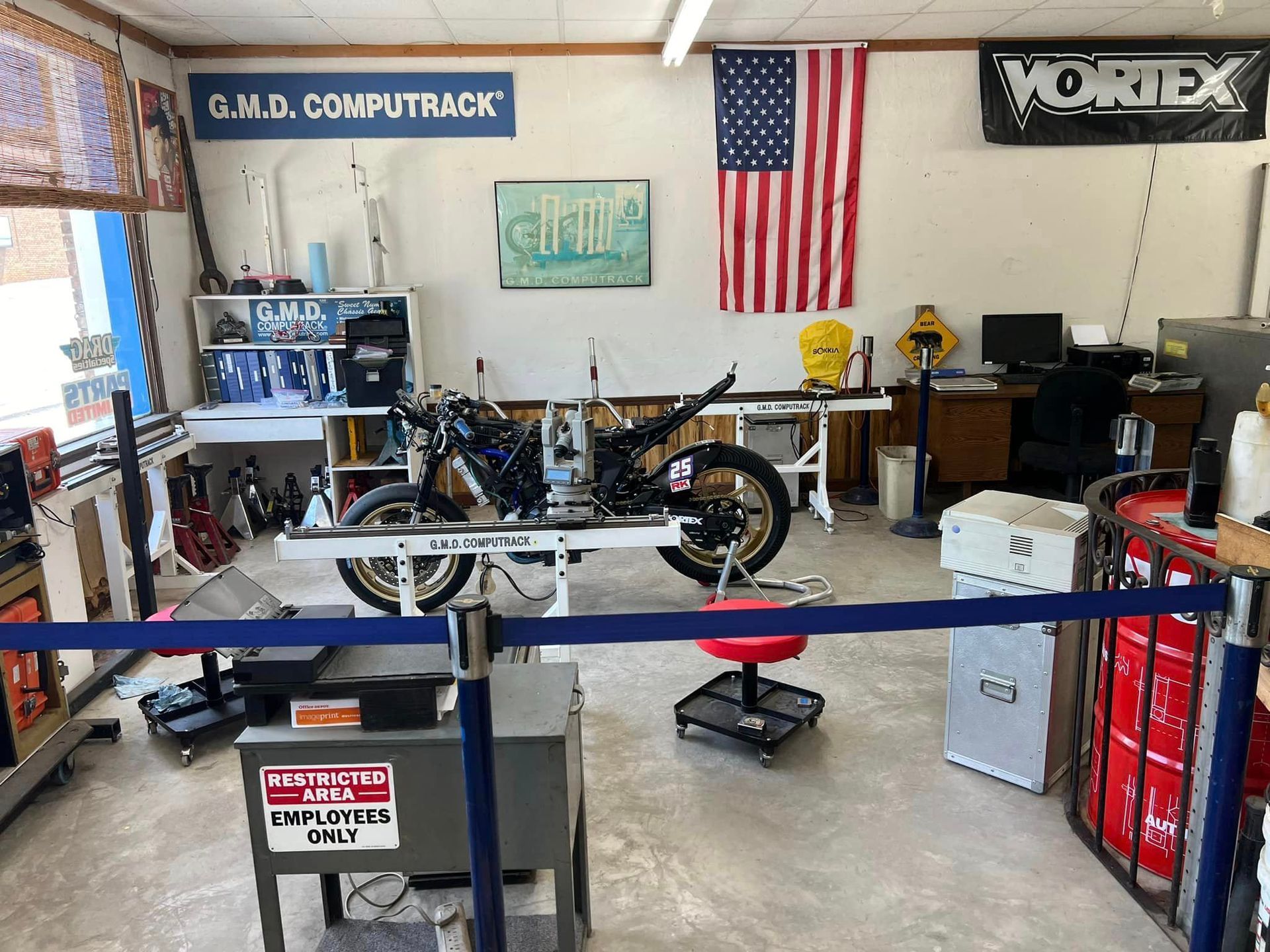 A vortex sign hangs above a motorcycle in a garage