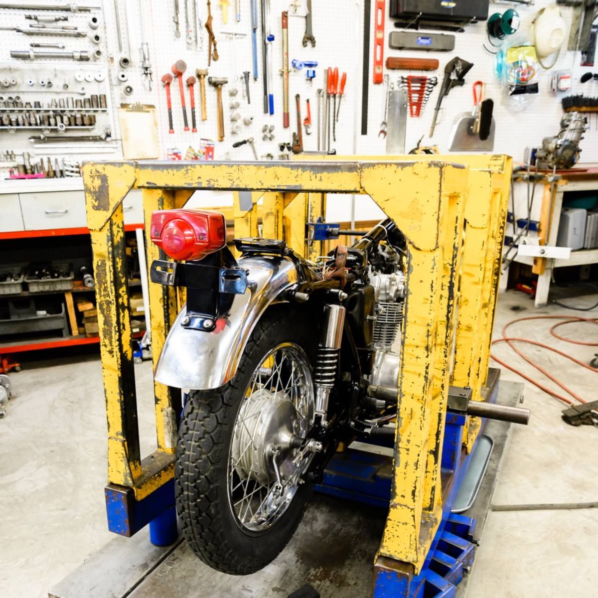 A motorcycle is sitting in a yellow frame in a garage