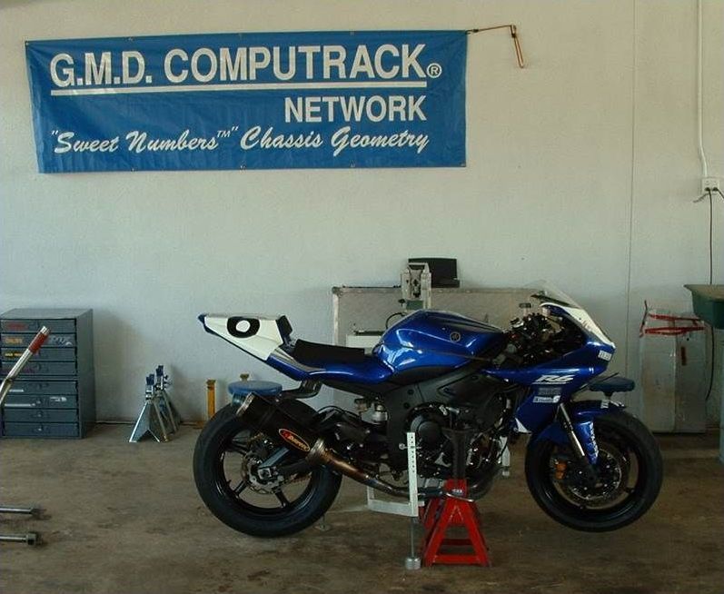 A blue motorcycle is parked under a sign that says g.m.d. computrack network