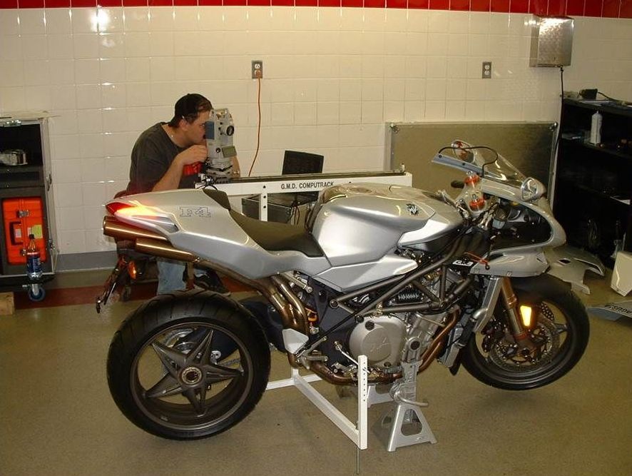 A man is working on a silver motorcycle in a garage