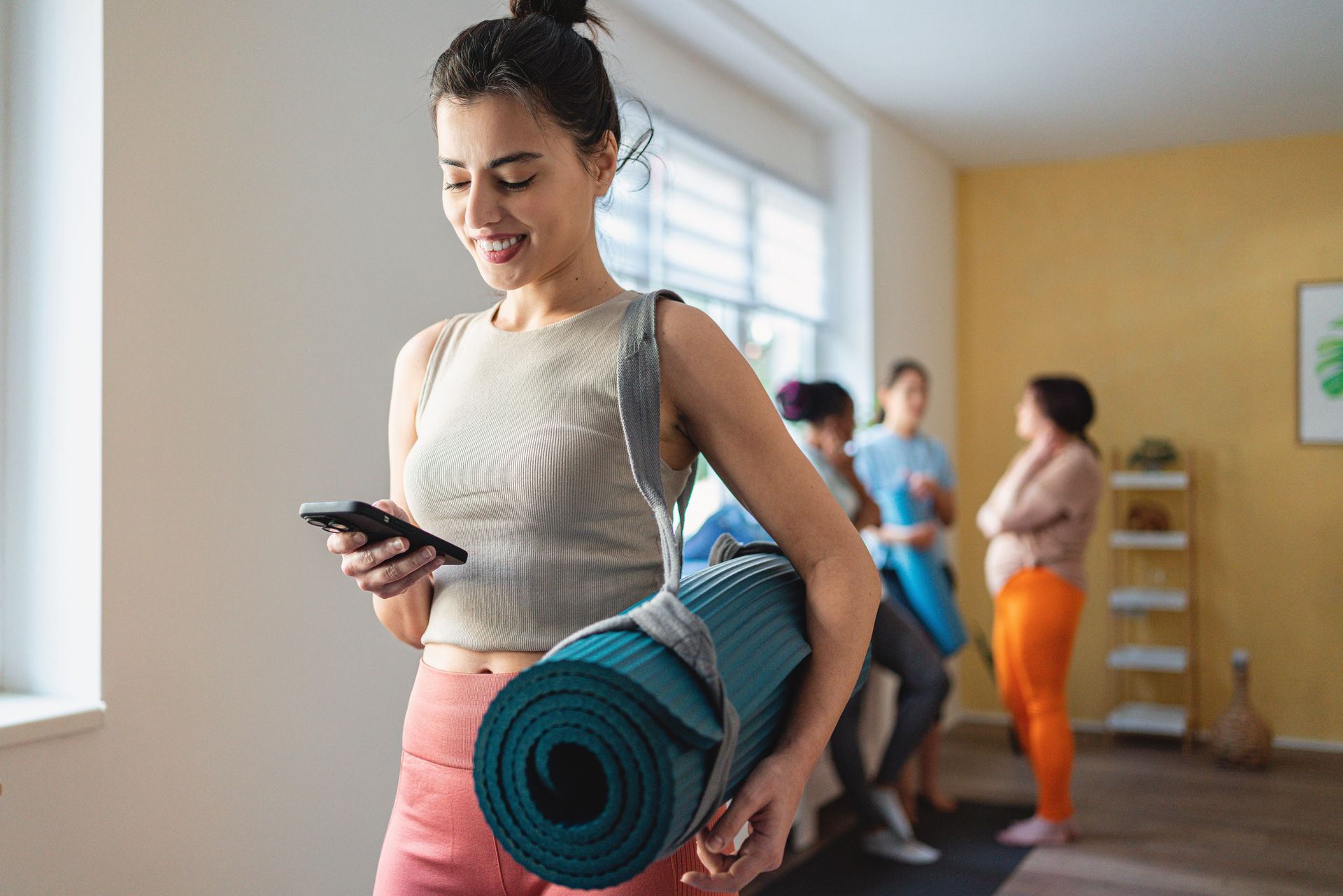 Women Using Phone After Exercise — Goodyear, AZ — Natalie's Fitness Elements Garage Women Using Phone After Exercise — Goodyear, AZ — Natalie's Fitness Elements Garage