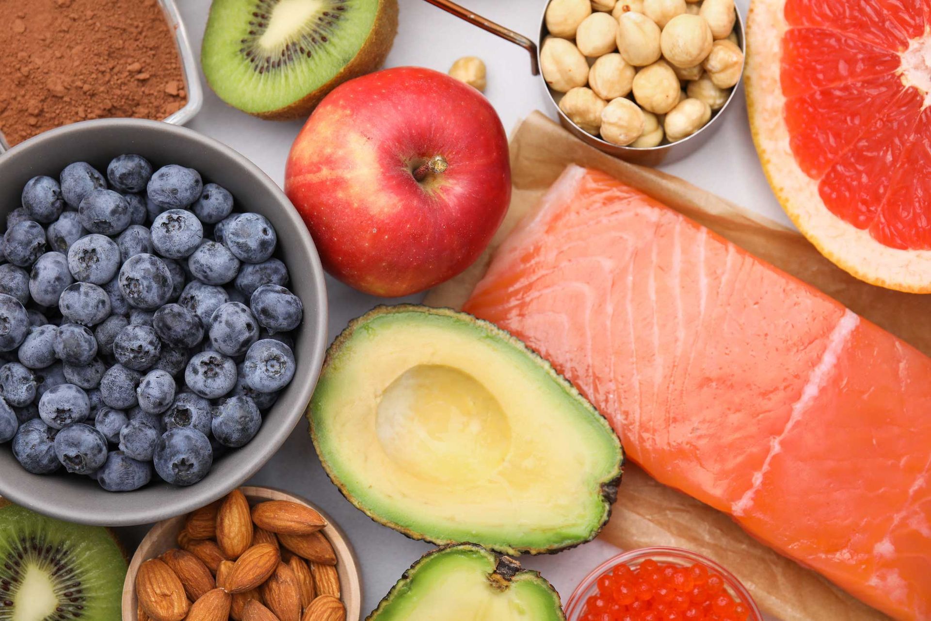 Assortment of colorful healthy foods: blueberries, apple, salmon, avocado, kiwi, nuts, grapefruit. Assortment of colorful healthy foods: blueberries, apple, salmon, avocado, kiwi, nuts, grapefruit.