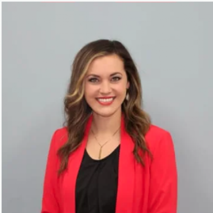 Smiling woman in a red blazer over a black top against a gray background