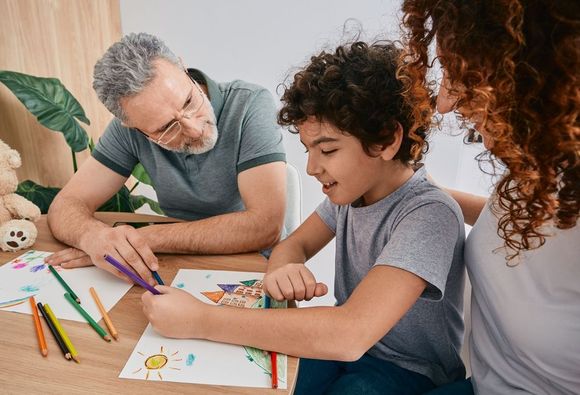 Family drawing together at a table with pencils and colorful paper