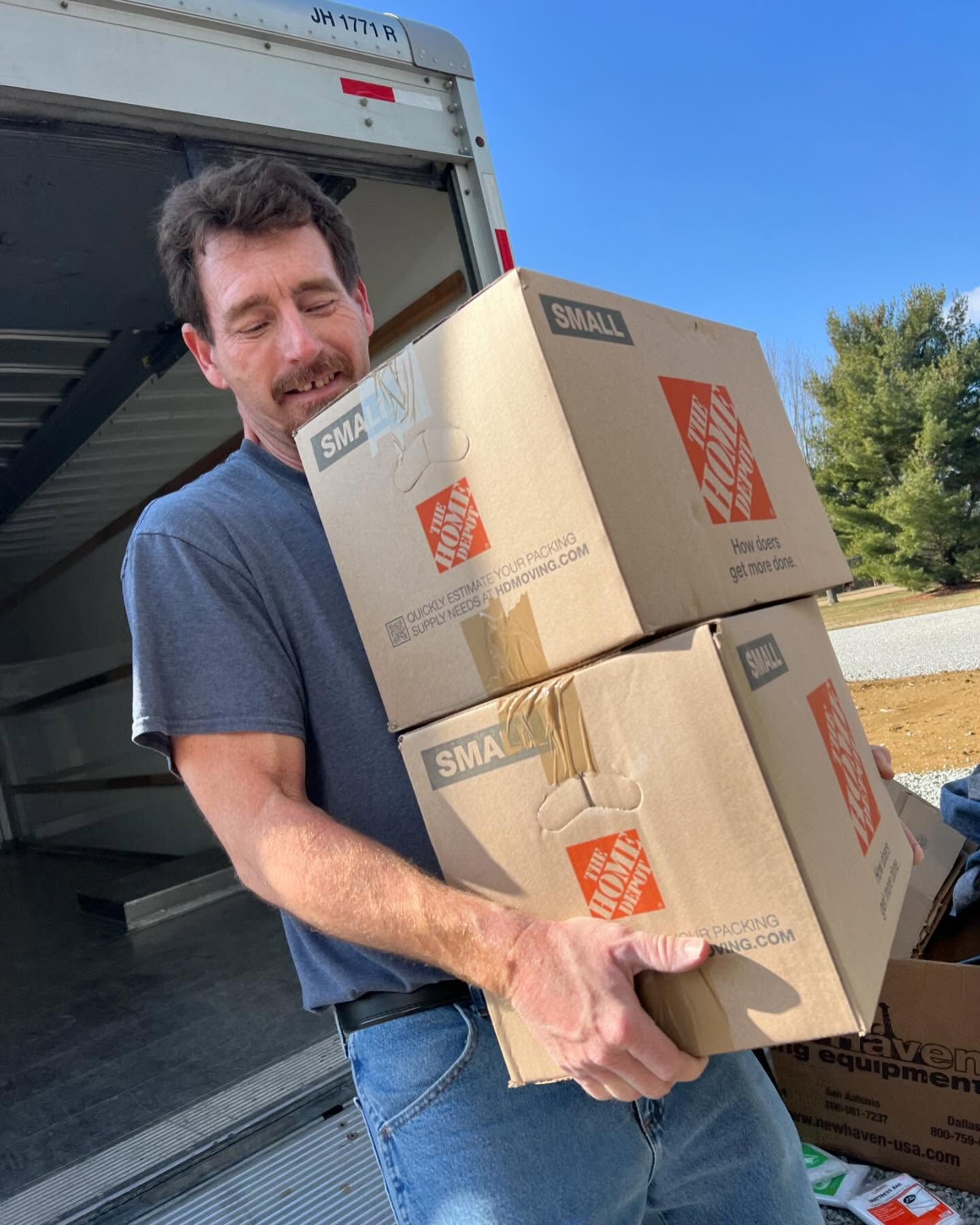 A man is carrying a stack of home depot boxes.