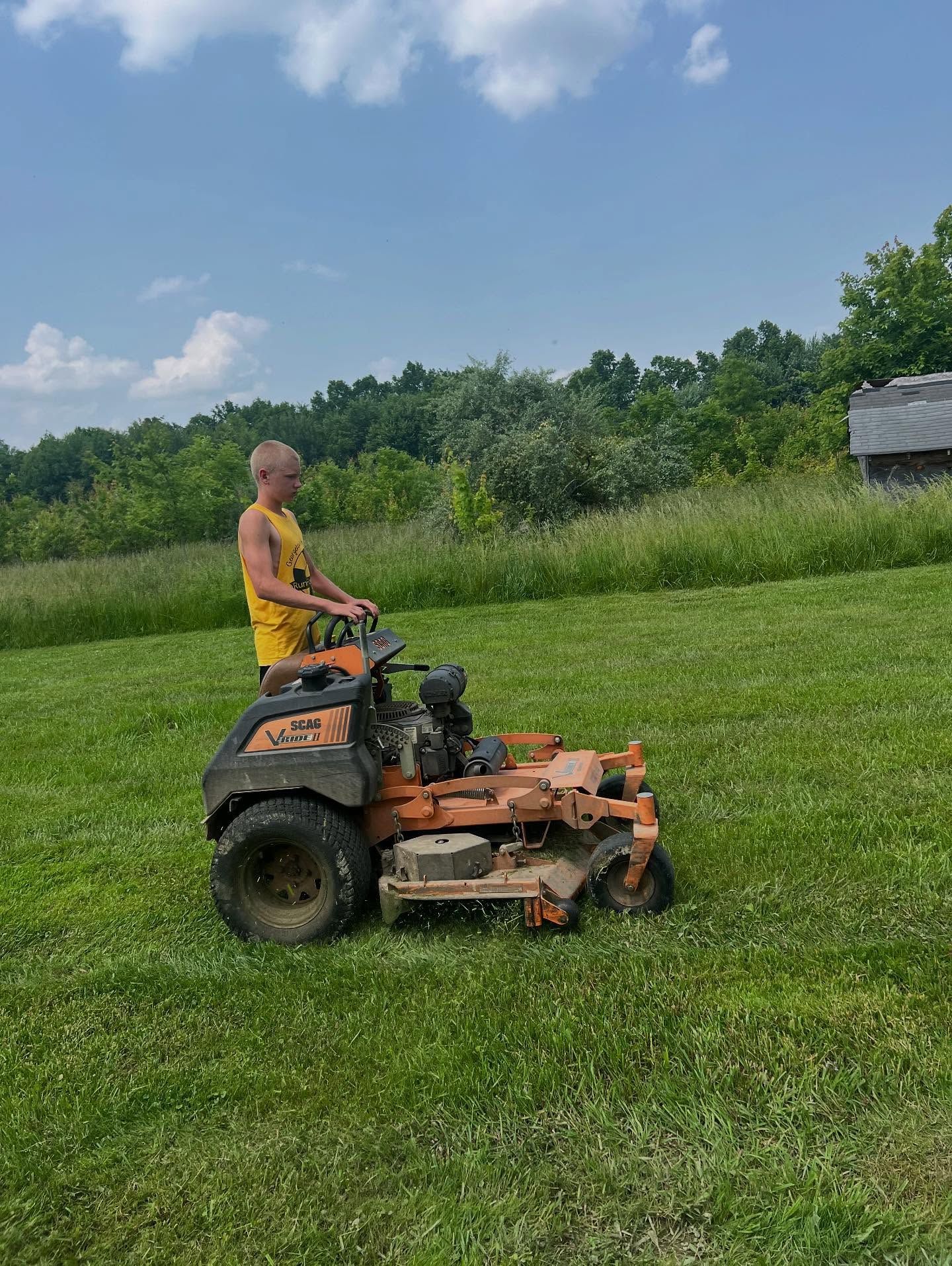 A man is riding a lawn mower on a lush green field.