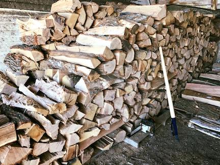 A pile of wood is sitting on the ground next to a shovel.