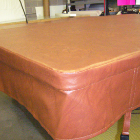 Close-up of a rectangular, brown leather cover, possibly for a table or spa.