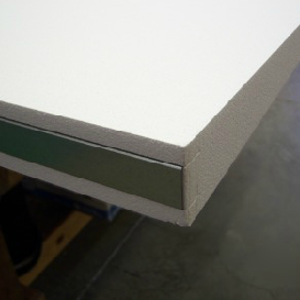Close-up view of a white insulated panel with a metallic edge, likely for construction or insulation purposes.