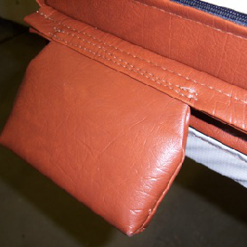 Close-up of a tan leather pouch attached to a seam. The pouch is rectangular and appears soft.