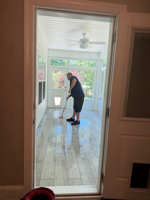 Person mopping a shiny porch floor seen through a doorway